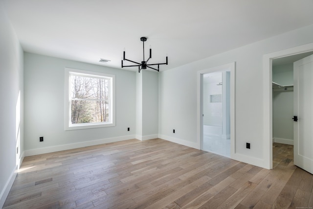 68 Paxton Ct, Goshen, CT 06756 - unfurnished bedroom featuring a chandelier, light wood-style flooring, a spacious closet, baseboards, and connected bathroom