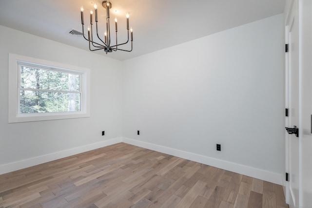 unfurnished dining area with baseboards, visible vents, light wood finished floors, and an inviting chandelier