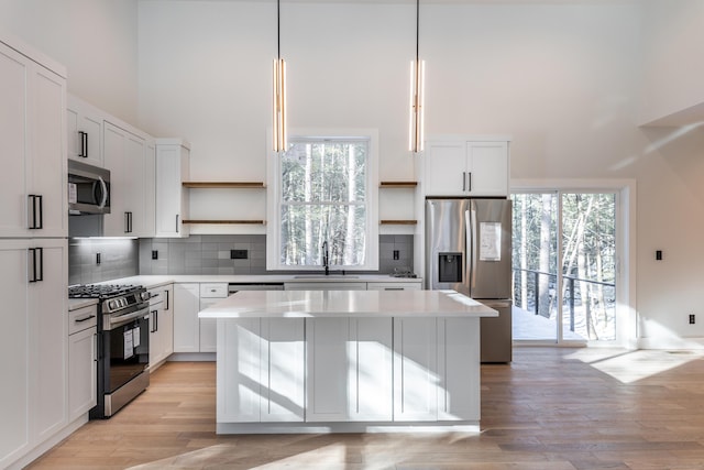 kitchen with open shelves, a kitchen island, a sink, and stainless steel appliances