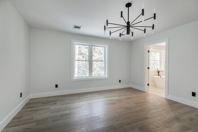 unfurnished room with light wood-style floors, visible vents, baseboards, and an inviting chandelier