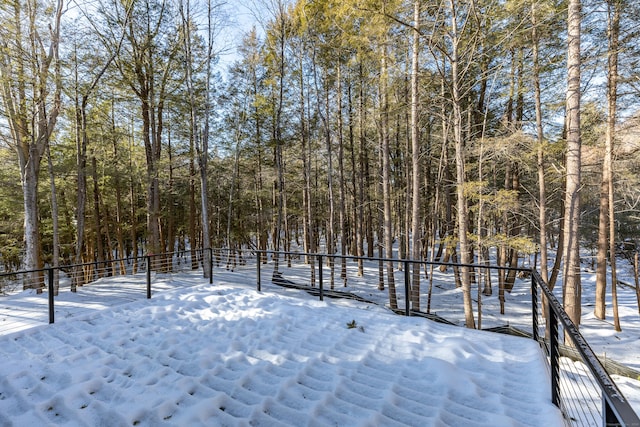 yard layered in snow featuring a view of trees