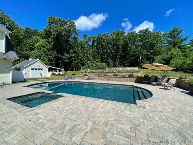 view of pool featuring a patio area and an in ground hot tub