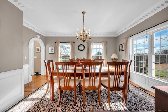 23 Olmstead Rd, East Haddam, CT 06423 - dining area featuring a chandelier, light wood finished floors, a wainscoted wall, crown molding, and arched walkways