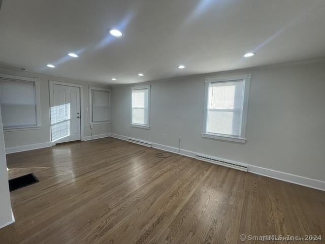 spare room with a baseboard heating unit, dark hardwood / wood-style flooring, and a healthy amount of sunlight