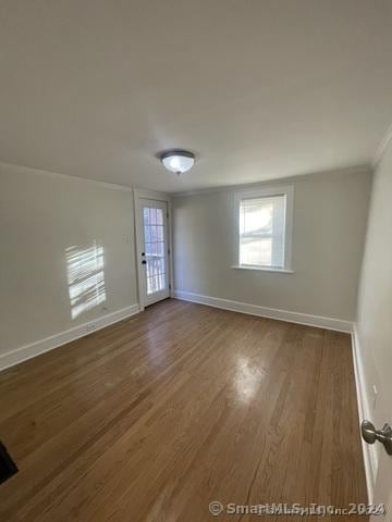 empty room with dark hardwood / wood-style floors and ornamental molding