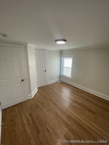 spare room with ornamental molding and dark wood-type flooring