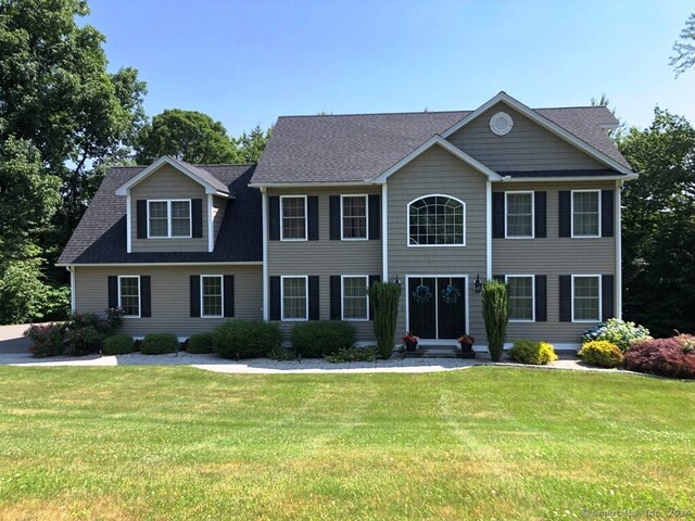 colonial-style house featuring a front yard