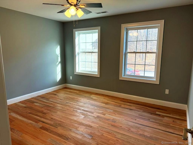 empty room with plenty of natural light, ceiling fan, and light wood-type flooring