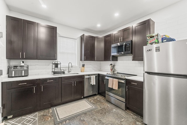 kitchen with appliances with stainless steel finishes, tasteful backsplash, dark brown cabinetry, and sink