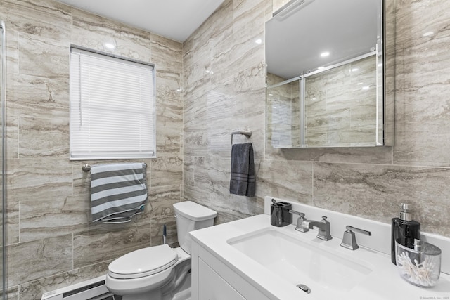 bathroom with toilet, a shower with shower door, a baseboard heating unit, tile walls, and vanity