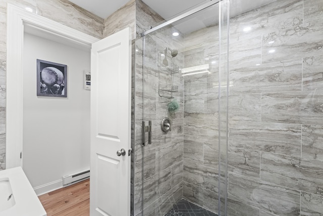 bathroom featuring baseboard heating, wood-type flooring, a shower with door, and vanity