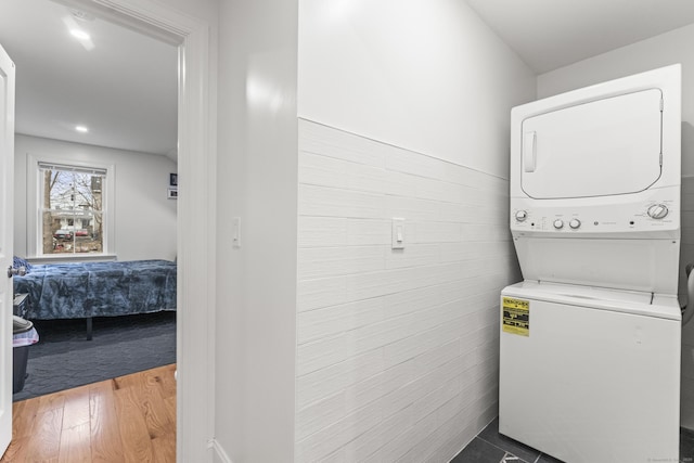 laundry room featuring stacked washer / drying machine and hardwood / wood-style floors