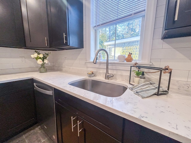 kitchen with light stone countertops, sink, stainless steel dishwasher, and tasteful backsplash