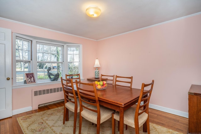 dining space with hardwood / wood-style floors, radiator, and ornamental molding