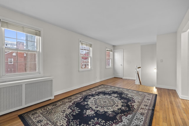 empty room featuring radiator heating unit, light wood-type flooring, and plenty of natural light