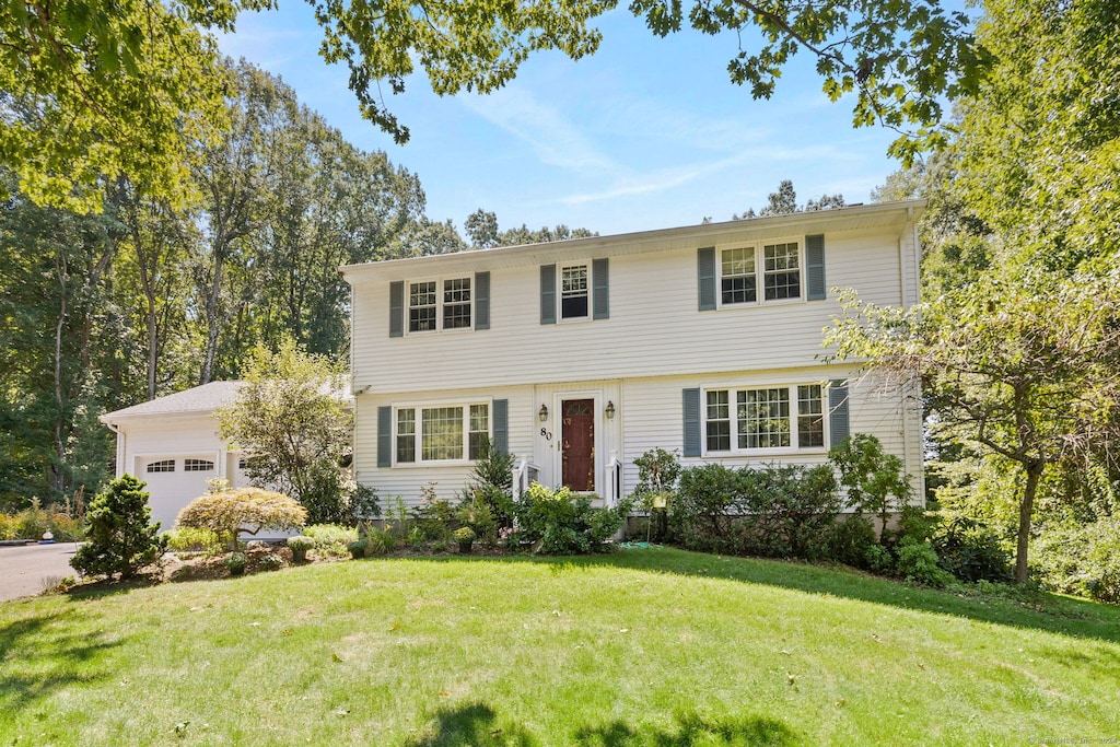 colonial house with a garage and a front lawn