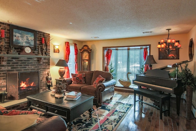 living room featuring hardwood / wood-style flooring, a textured ceiling, a brick fireplace, and an inviting chandelier