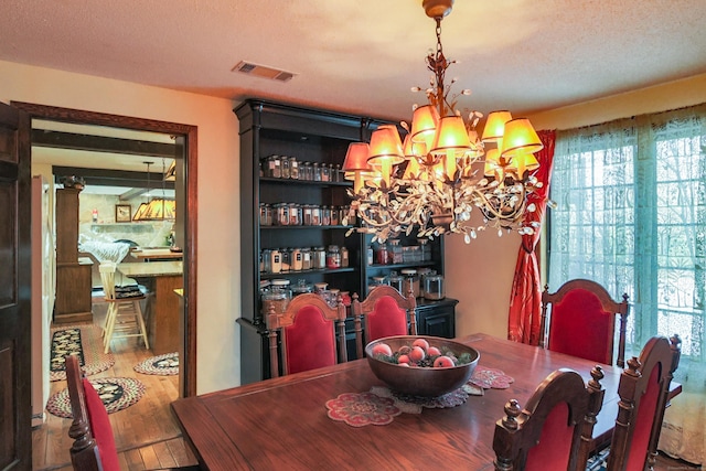 dining space with a chandelier, a textured ceiling, and hardwood / wood-style flooring