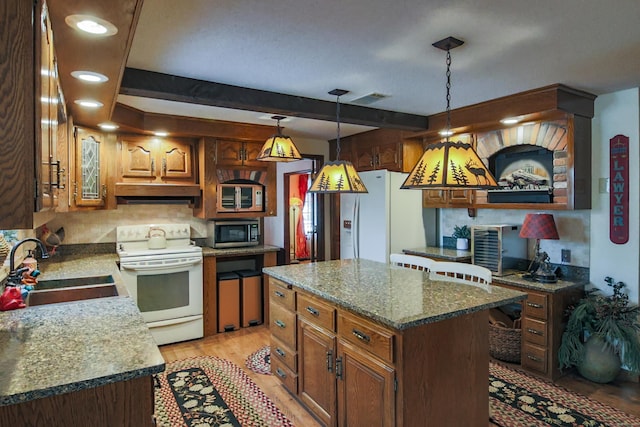 kitchen with a center island, sink, pendant lighting, white appliances, and light wood-type flooring