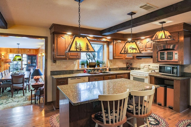 kitchen with a center island, white appliances, sink, and light hardwood / wood-style flooring