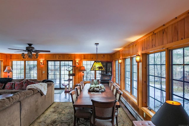 dining space with ceiling fan, baseboard heating, ornamental molding, wood walls, and hardwood / wood-style flooring