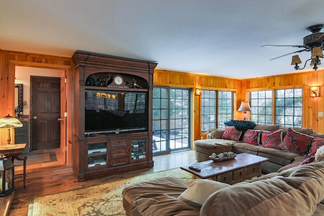 living room featuring ceiling fan, wooden walls, and hardwood / wood-style floors