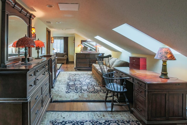 office space with a textured ceiling, light wood-type flooring, and lofted ceiling with skylight