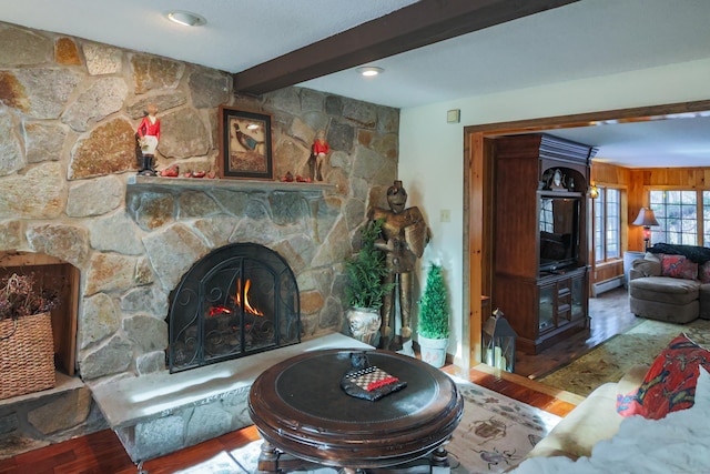 living room featuring beam ceiling, a stone fireplace, hardwood / wood-style floors, and a baseboard radiator