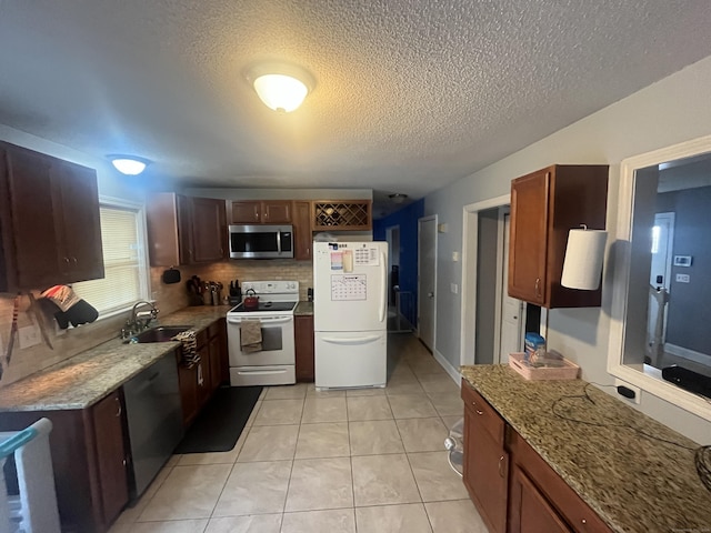 kitchen featuring light stone counters, white appliances, sink, and light tile patterned floors