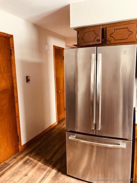 kitchen featuring baseboards, brown cabinets, wood finished floors, and freestanding refrigerator