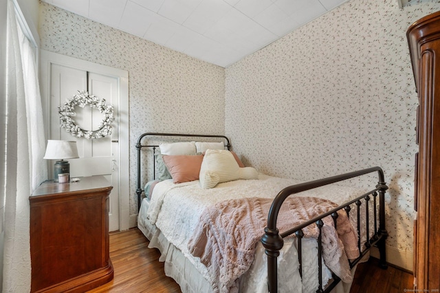 bedroom with wood finished floors and wallpapered walls