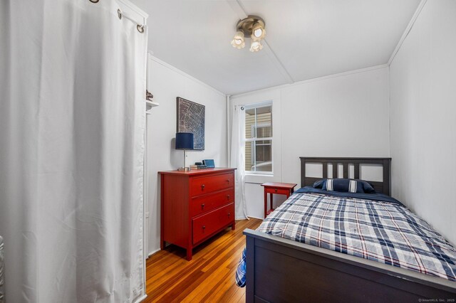 bedroom with ornamental molding and dark wood-type flooring