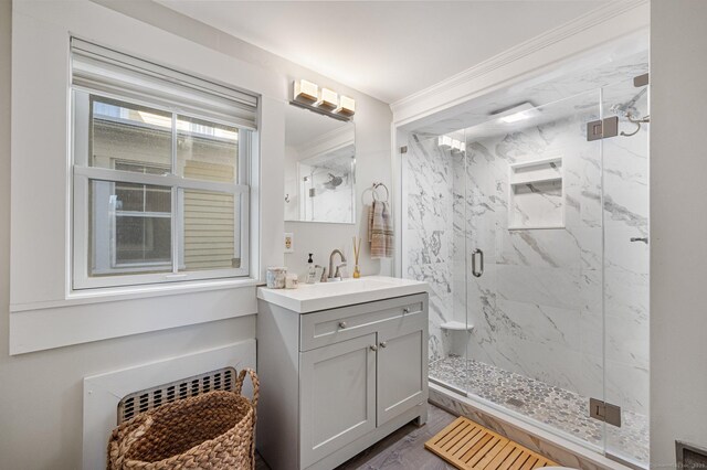 bathroom with radiator, ornamental molding, a shower with shower door, and vanity