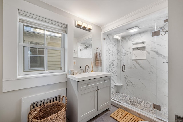 bathroom featuring vanity, radiator, a marble finish shower, crown molding, and wood finished floors