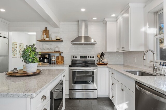 kitchen featuring wall chimney exhaust hood, stainless steel appliances, decorative backsplash, white cabinets, and sink