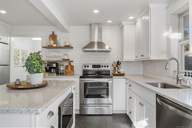 kitchen with stainless steel appliances, tasteful backsplash, a sink, open shelves, and wall chimney range hood