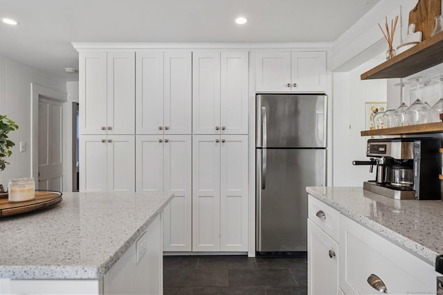 kitchen with recessed lighting, white cabinetry, open shelves, light stone counters, and freestanding refrigerator