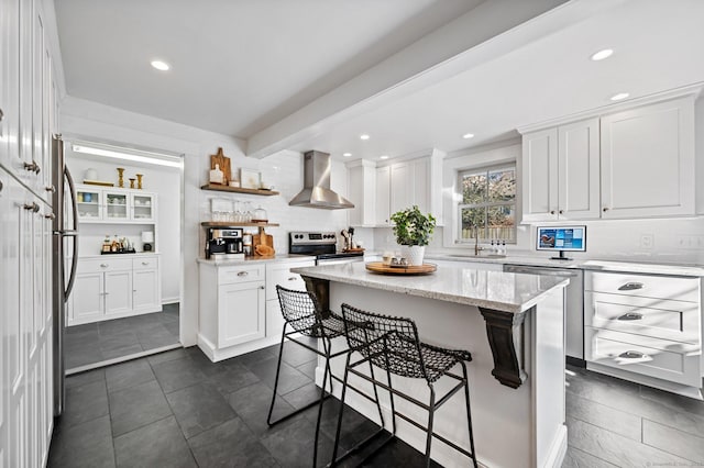 kitchen with a sink, white cabinetry, wall chimney exhaust hood, tasteful backsplash, and stainless steel appliances