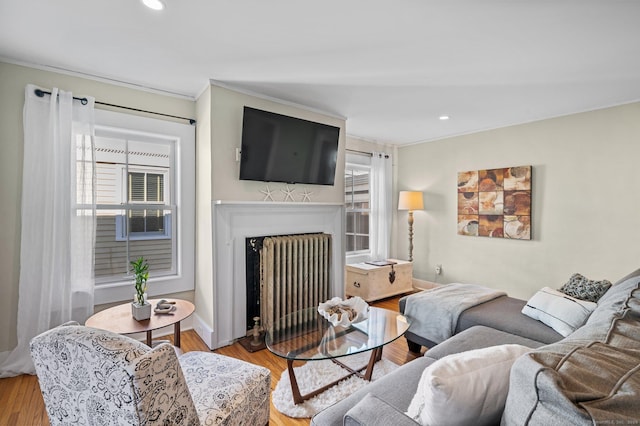 living room featuring recessed lighting, ornamental molding, a fireplace with flush hearth, and wood finished floors