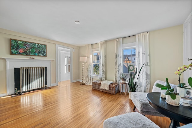 living room featuring radiator, a fireplace, and light wood-type flooring