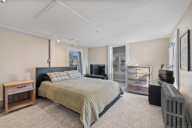 carpeted bedroom with attic access and track lighting