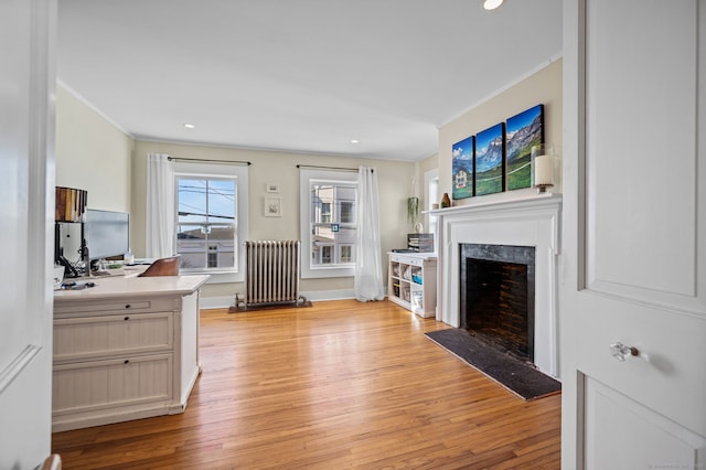 living area with ornamental molding, radiator, and light wood-style floors