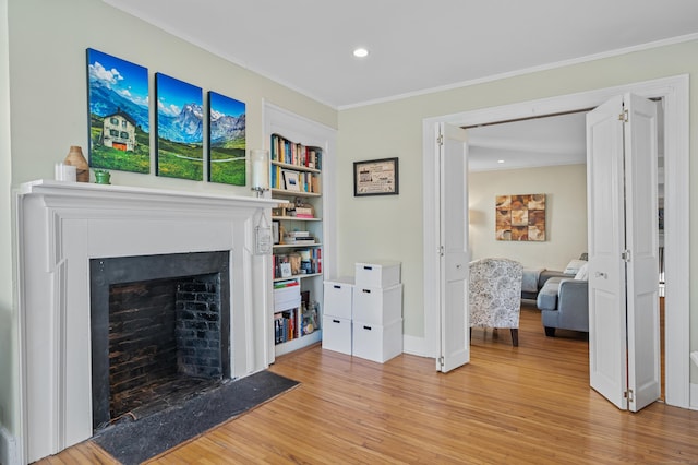 living room with light hardwood / wood-style floors, ornamental molding, and built in shelves