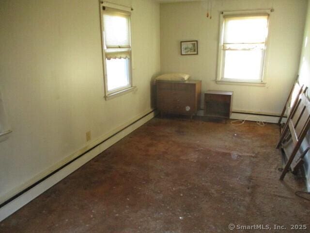 empty room featuring baseboard heating and a healthy amount of sunlight