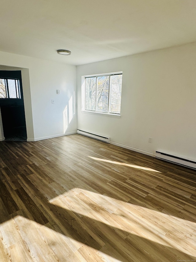 empty room with hardwood / wood-style floors and baseboard heating