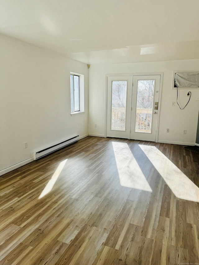 unfurnished room featuring a wealth of natural light, hardwood / wood-style floors, and a baseboard radiator