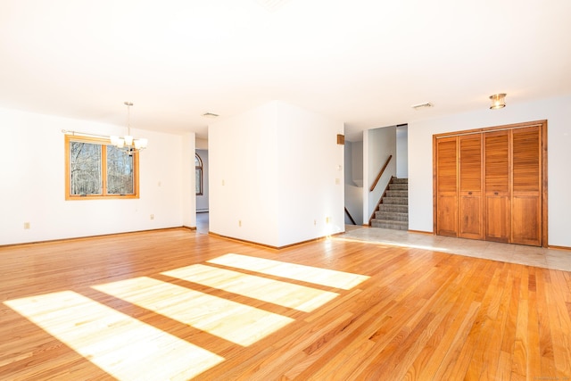 unfurnished living room with a notable chandelier and light wood-type flooring