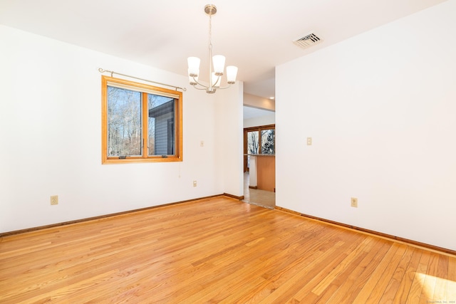 unfurnished room with a notable chandelier and light hardwood / wood-style flooring