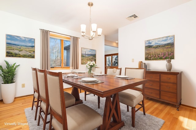 dining room with light hardwood / wood-style floors and an inviting chandelier