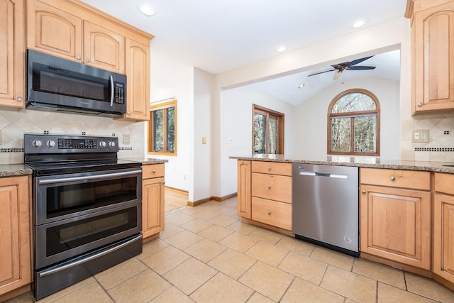 kitchen with backsplash, light stone counters, stainless steel appliances, vaulted ceiling, and ceiling fan